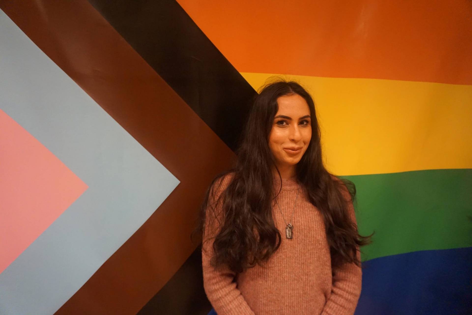 Eine Frau steht vor einer LGBTIQ-Flagge